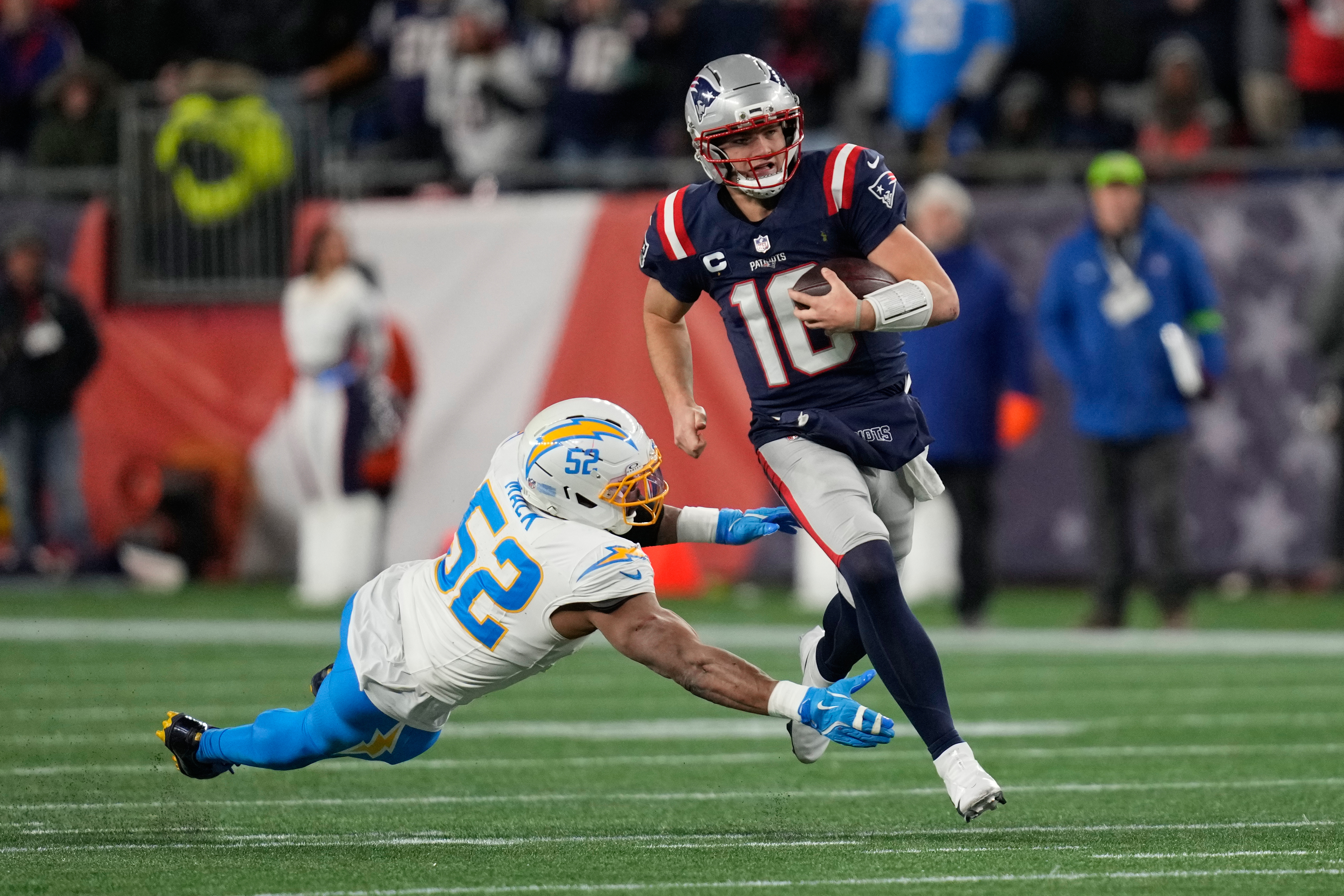 New England Patriots quarterback Drake Maye (10) avoids a tackle by Los Angeles Chargers linebacker Khalil Mack (52) in the first half of an NFL wild-card playoff football game in Foxborough, Mass., Sunday, Jan. 11, 2026.
