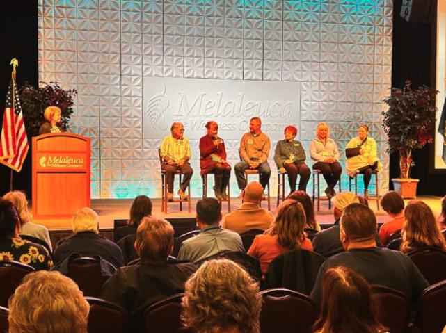 Sharon Eubank, the humanitarian director for The Church of Jesus Christ of Latter-day Saints, speaks at the podium, left, on stage with six representatives of local organizations.