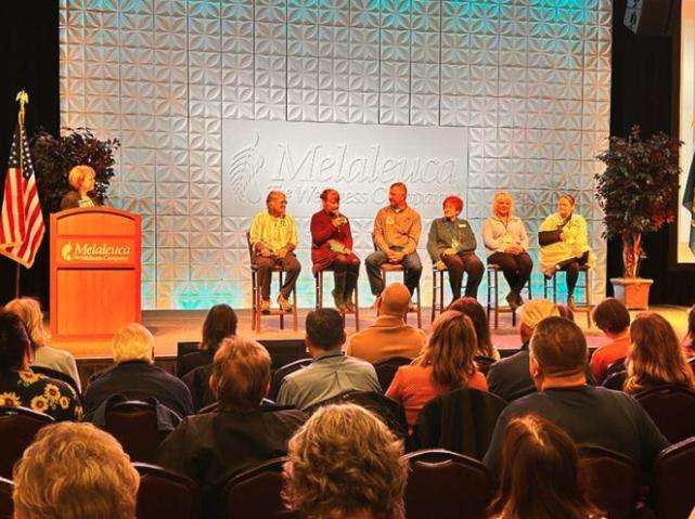 Sharon Eubank, the humanitarian director for The Church of Jesus Christ of Latter-day Saints, speaks at the podium, left, on stage with six representatives of local organizations.