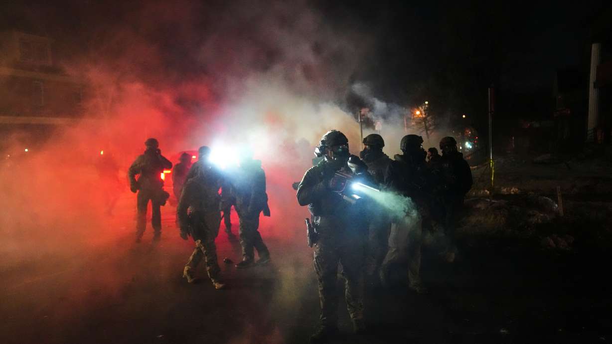 Law enforcement officers stand amid tear gas at the scene of a reported shooting Wednesday in Minneapolis.