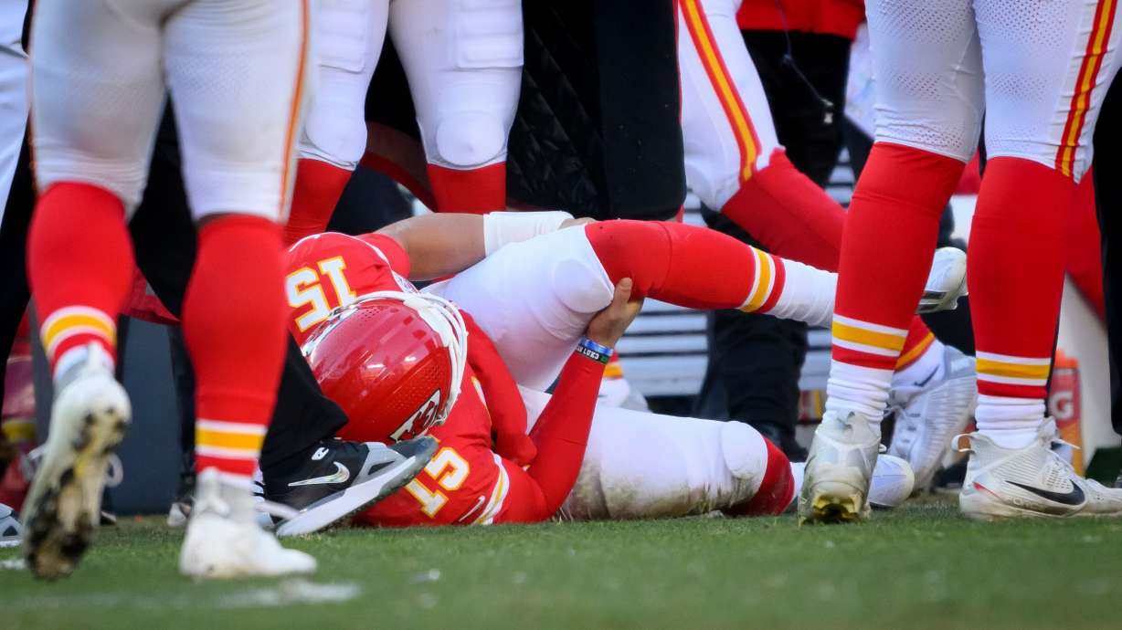 FILE - Kansas City Chiefs quarterback Patrick Mahomes (15) clutches his left knee after being injured during thine second half of an NFL football game against the Los Angeles Chargers, Sunday, Dec. 14, 2025 in Kansas City, Mo.