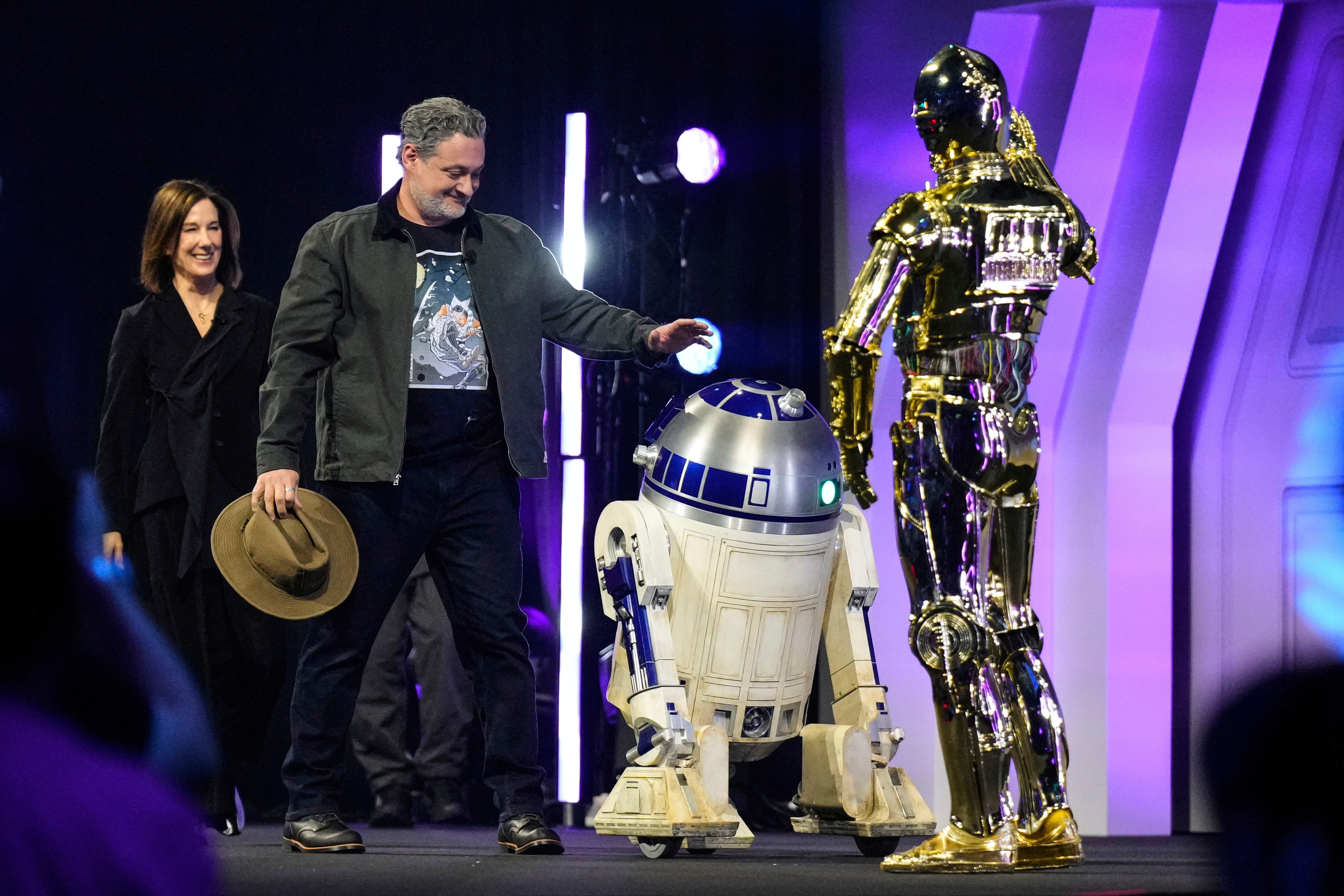 Film producer Kathleen Kennedy, left, and director Dave Filoni are welcomed by R2-D2 and C-3PO, right, as they appear on stage during a fan convention called the Star Wars Celebration in Chiba, Japan, April 18. Filoni will succeed Kennedy after Kennedy announced she would step down on Thursday.