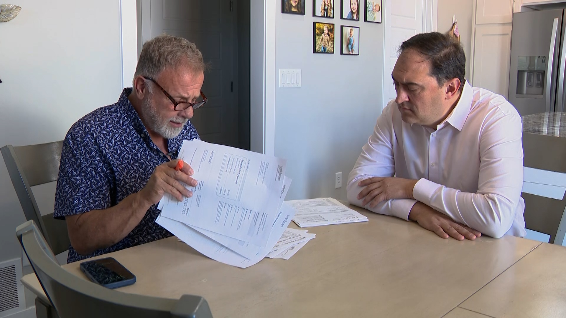 Mike De Mie does through his carrier’s billing documents with KSL’s Matt Gephardt, Thursday. De Mie did eventually get his problem with his carrier's "free phone" offer resolved.