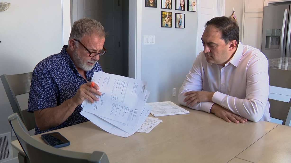 Mike De Mie does through his carrier’s billing documents with KSL’s Matt Gephardt, Thursday. De Mie did eventually get his problem with his carrier's "free phone" offer resolved.