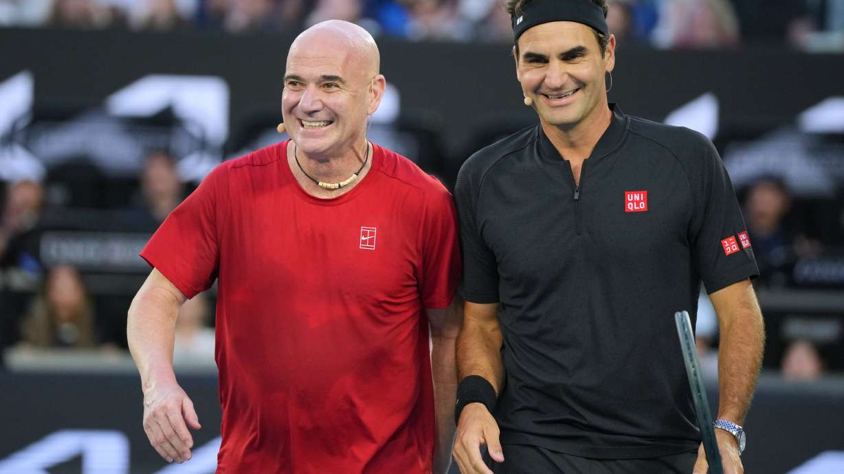 Roger Federer of Switzerland reacts with partner Andre Agassi, left, of the United States in their doubles match against Lleyton Hewitt and Pat Rafter of Australia during the Opening Ceremony for the Australian Open tennis championship in Melbourne, Australia, Saturday, Jan. 17, 2026.