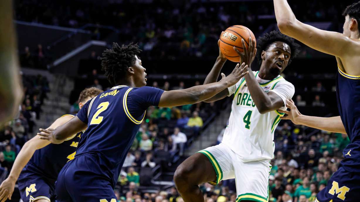 Oregon forward Dezdrick Lindsay (4), looks to pass against Michigan guard L.J. Cason (2) in the first half of an NCAA college basketball game in Eugene, Ore., Saturday, Jan. 17, 2026.
