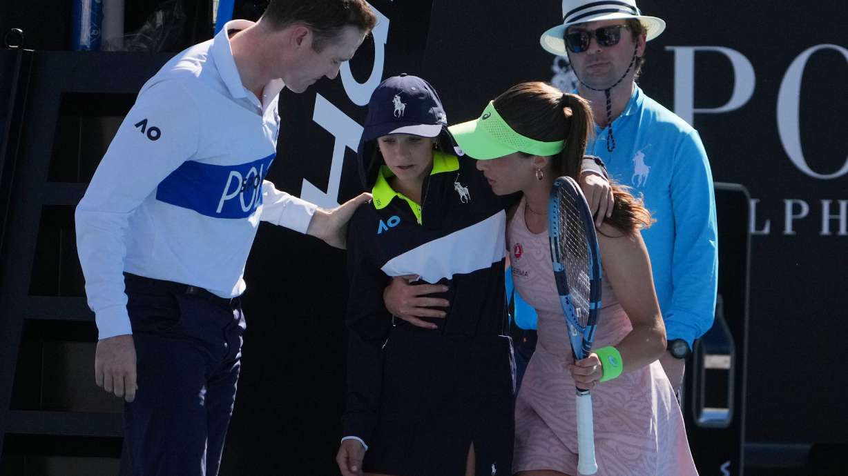 Zeynep Sonmez of Turkey and umpire Chase Urban help a ball kid who fainted, from the court during her first round match against Ekaterina Alexandrova of Russia at the Australian Open tennis championship in Melbourne, Australia, Sunday, Jan. 18, 2026.