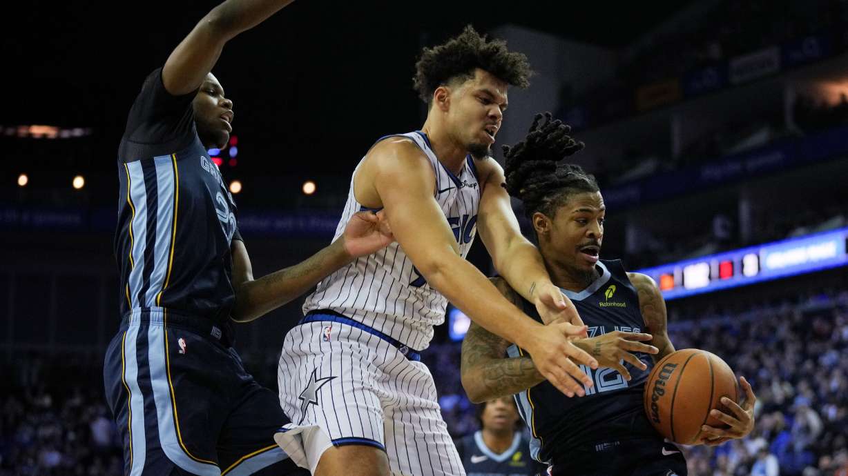 Orlando Magic forward Noah Penda, center, Memphis Grizzlies forward Cedric Coward, left and Memphis Grizzlies guard Ja Morant, right, fight for the ball during the first half of an NBA basketball game Sunday, Jan. 18, 2026, in London.