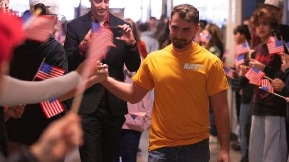 Sean Steo high-fives students as he walks down the hallway on Thursday. Students lined the hallways waving American flags at Eagle Rock Middle School Thursday afternoon in a surprise send-off for their PE teacher, Steo, who is joining the U.S. Navy.