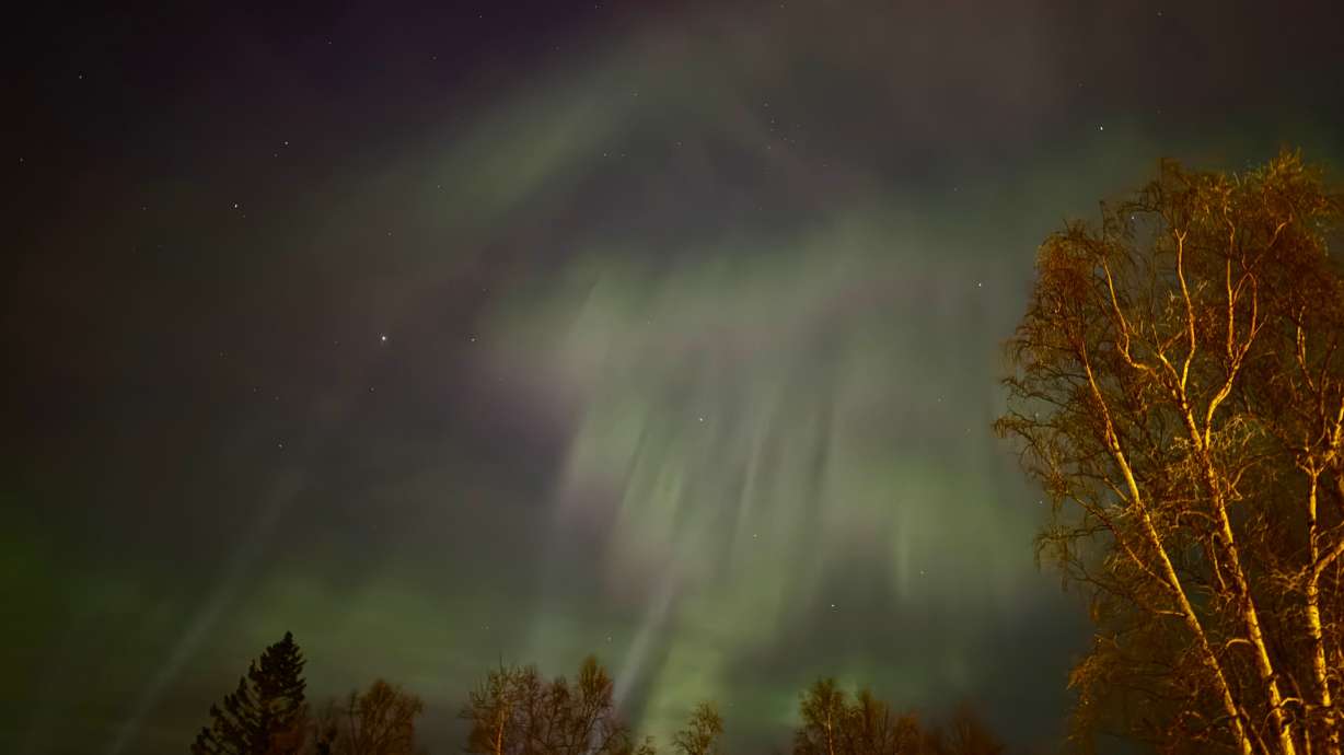 The northern lights illuminate the sky over Anchorage, Alaska, Tuesday. Streaks of shimmering green and red bands exploded in the dark skies as the aurora provided a light show for early morning dog walkers, joggers and commuters.