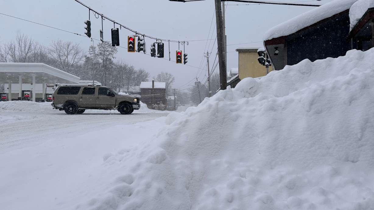 Traffic passes piled-up snow in Lowville, N.Y., Tuesday, Jan. 20, 2026.
