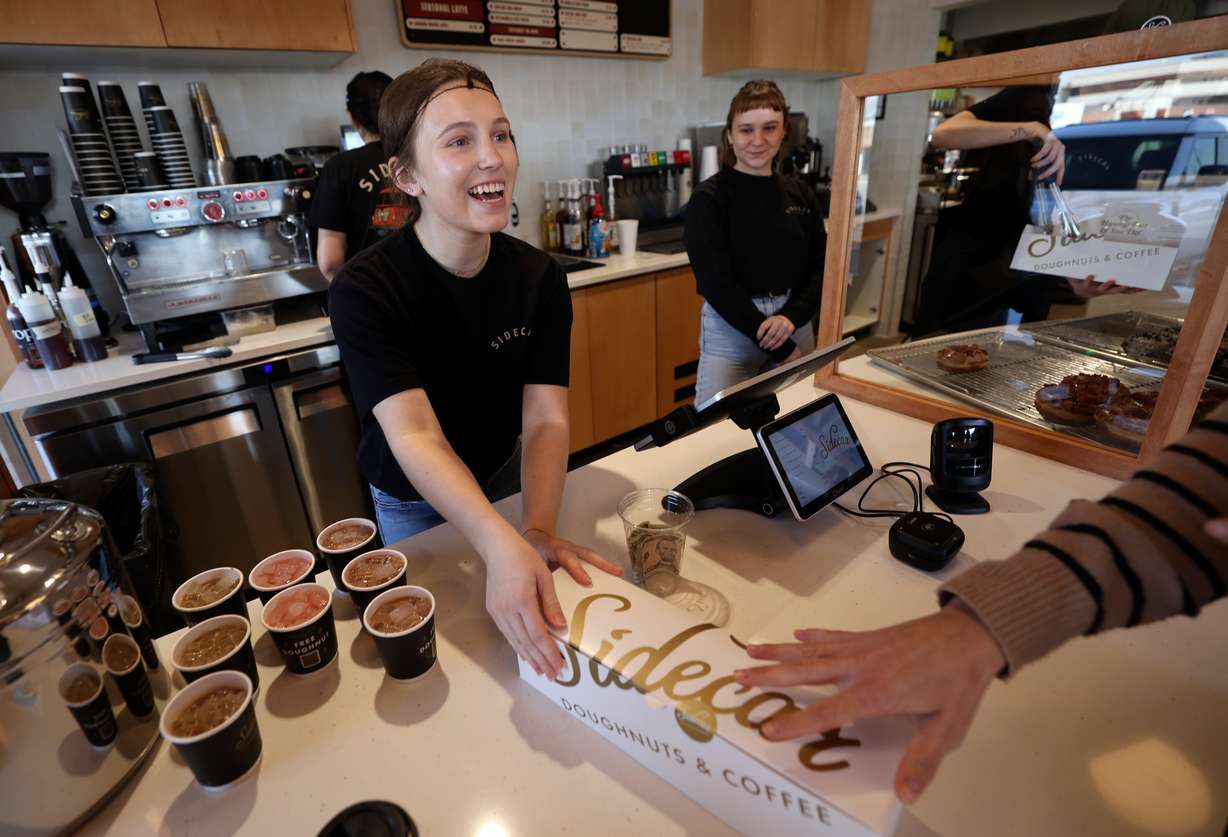 Maddie Rowsey hands doughnuts to a customer at the ribbon-cutting event for Sidecar Doughnuts and Coffee in Salt Lake City on Wednesday.