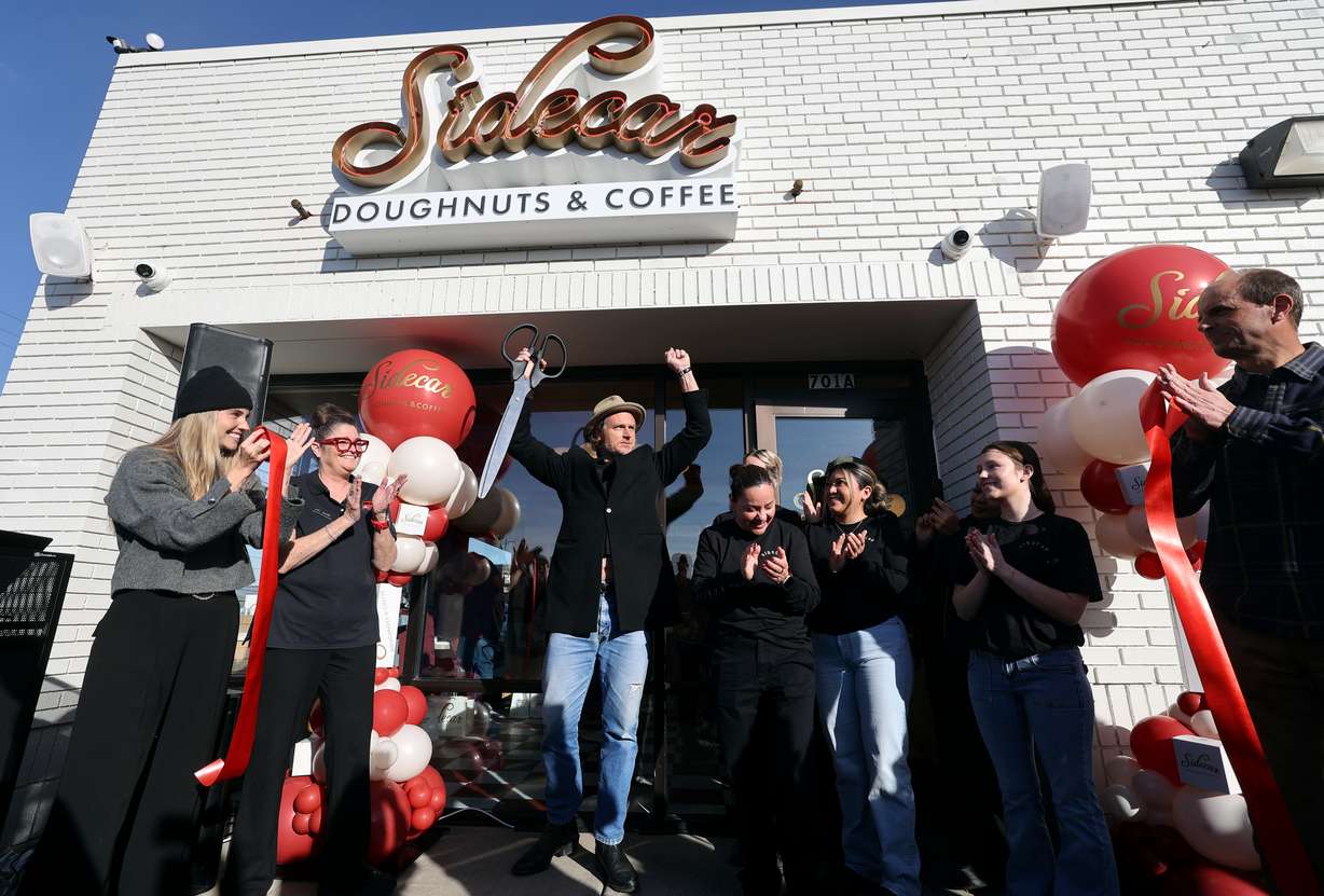 Sumter Pendergrast, Sidecar Doughnuts founder, raises his arms after cutting the ribbon for the ribbon-cutting ceremony for Sidecar Doughnuts and Coffee in Salt Lake City on Wednesday.