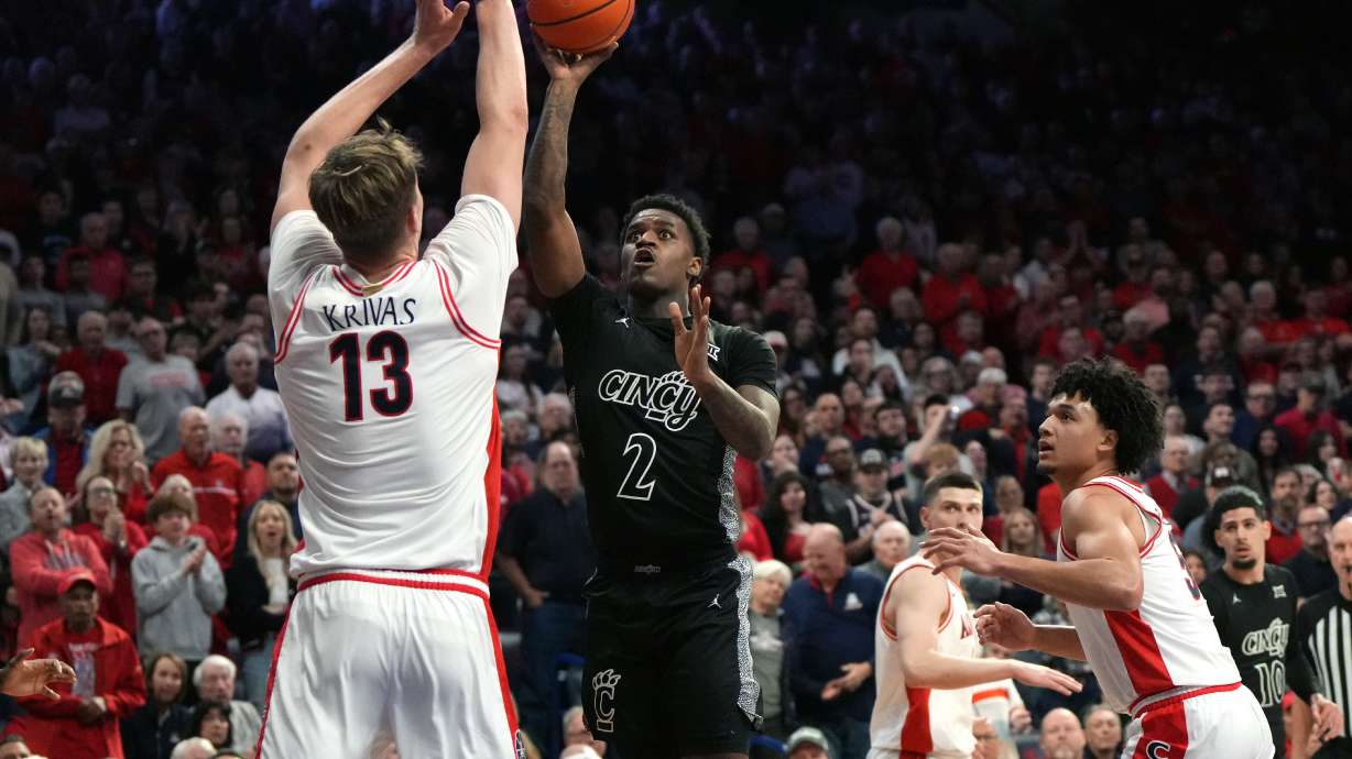 Cincinnati guard Jizzle James drives on Arizona center Motiejus Krivas and guard Brayden Burries (5) during the first half of an NCAA college basketball game, Wednesday, Jan. 21, 2026, in Tucson, Ariz.