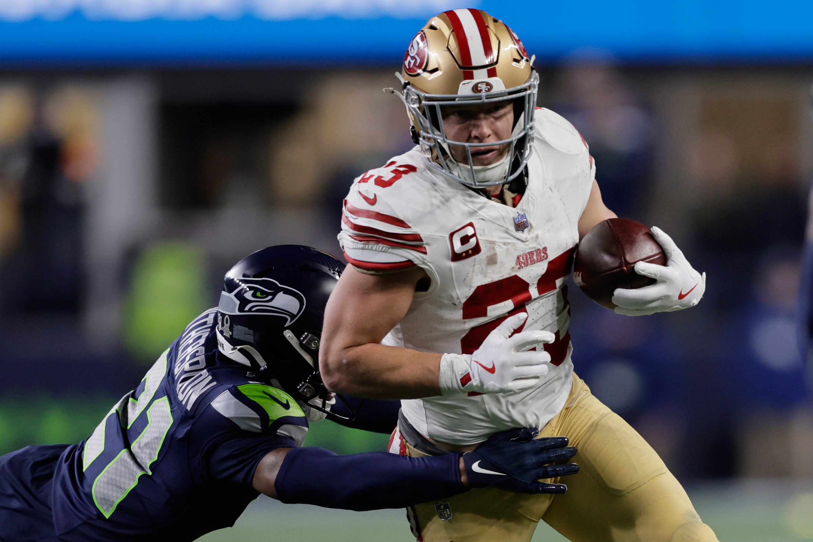 San Francisco 49ers running back Christian McCaffrey (23) tries to get past the Seattle Seahawks cornerback Devon Witherspoon during the first half of an NFL football divisional playoff game Saturday, Jan. 17, 2026, in Seattle. 