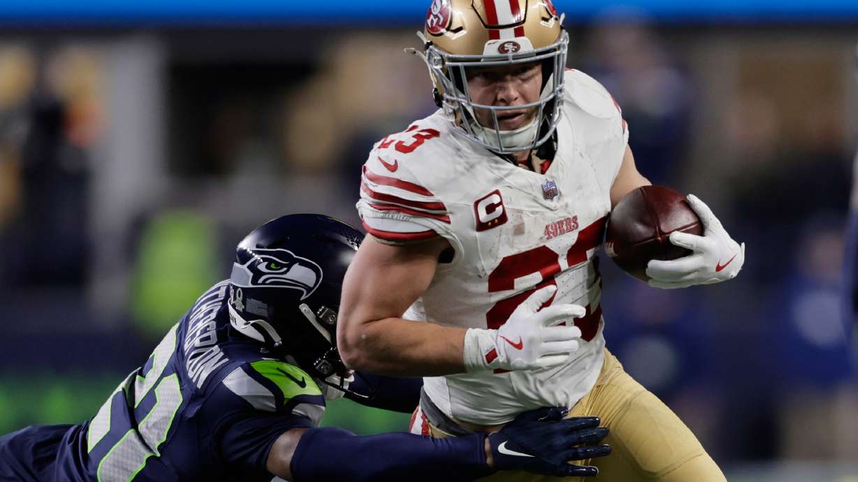 San Francisco 49ers running back Christian McCaffrey (23) tries to get past the Seattle Seahawks cornerback Devon Witherspoon during the first half of an NFL football divisional playoff game Saturday, Jan. 17, 2026, in Seattle.