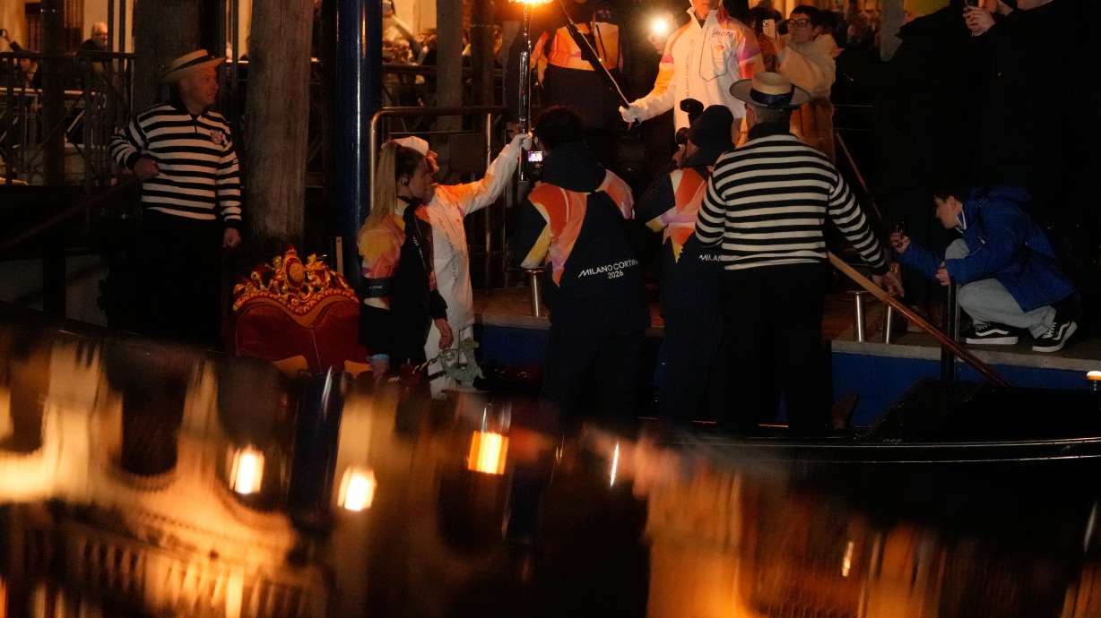 Torchbearers hold the Olympic torches flame on the Grand Canal in Venice, Italy, Thursday, Jan. 22, 2026, its journey will conclude in Milan on February 6 for the Winter Olympics opening ceremony.