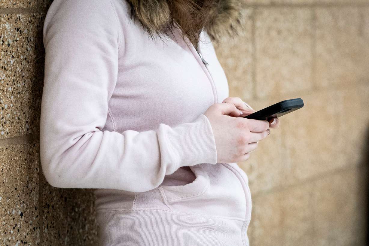 A student uses a cellphone in a hallway at Olympus High School in Holladay on Jan. 8.