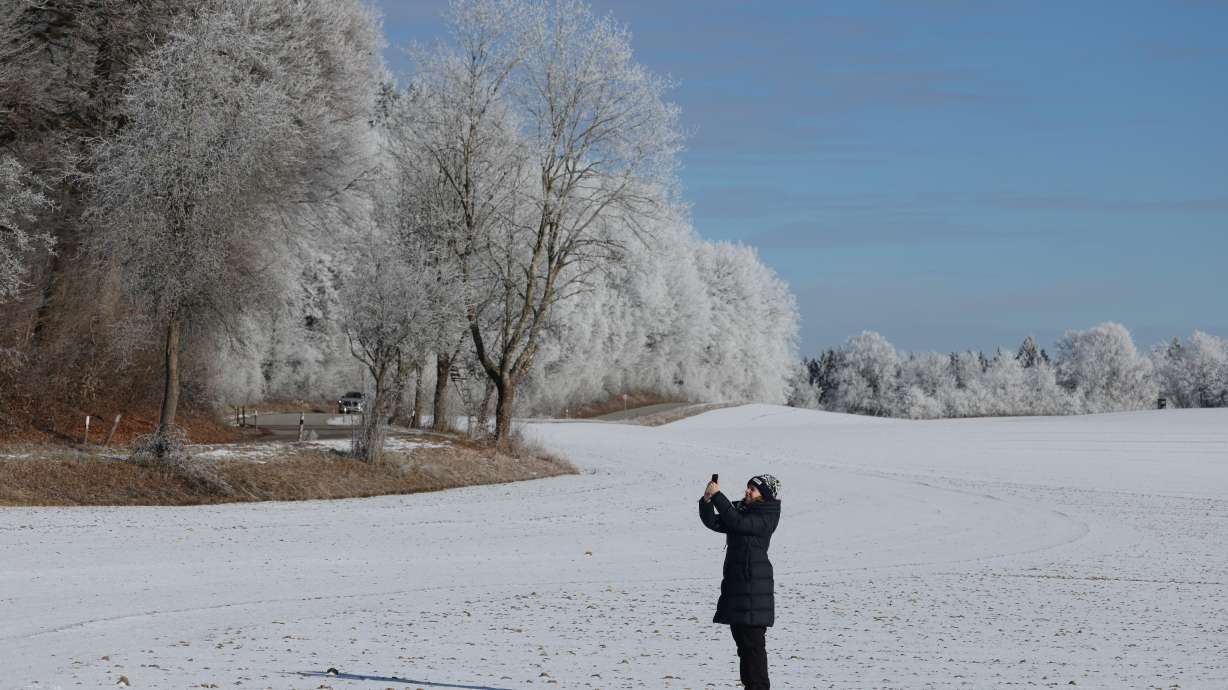 A woman snaps photos of snow- and frost-covered trees near Kottgeisering, Germany.