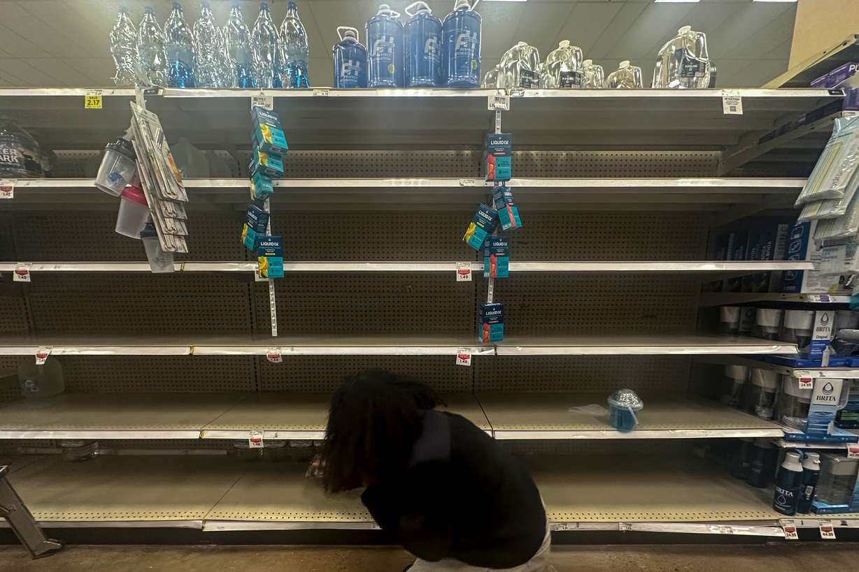 A shopper searches for water on near empty shelves in grocery store ahead of winter weather, Wednesday, in Marietta, Ga. People are stocking up and flights are already being disrupted as a winter storm moves in.