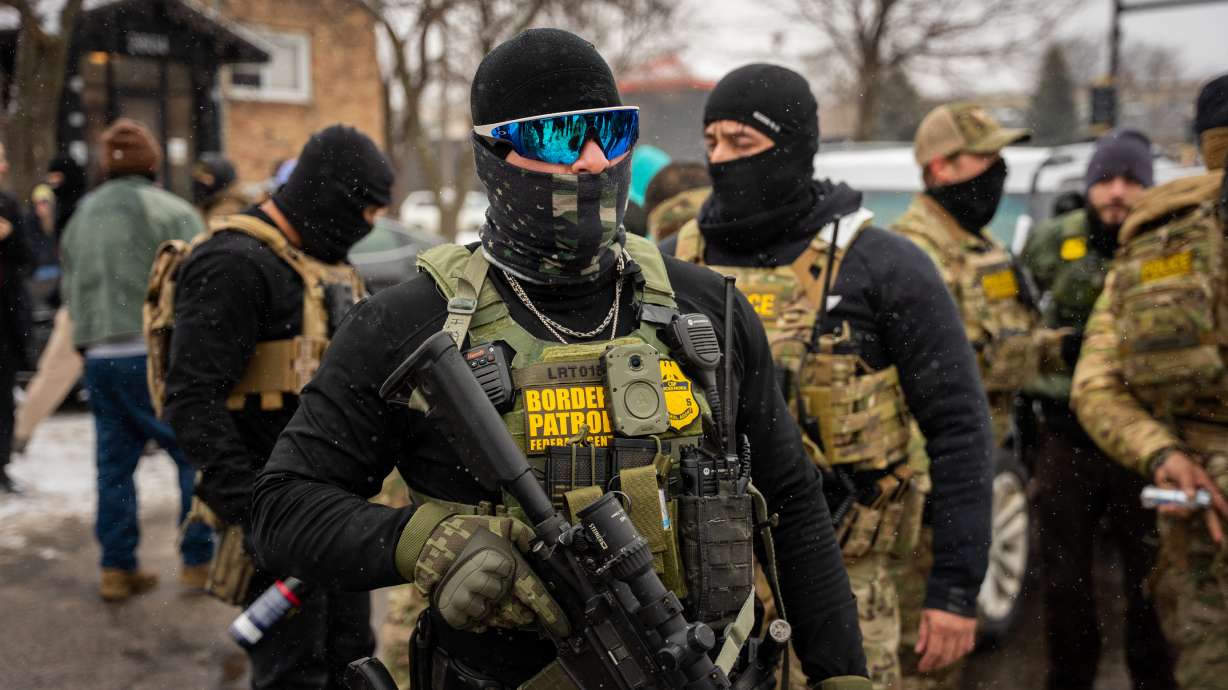 Federal agents stand guard, Wednesday in Minneapolis. A vast network of labor unions, progressive organizations and clergy is asking Minnesotans to stay away from work, school and stores in protest at immigration enforcement operations in the state.
