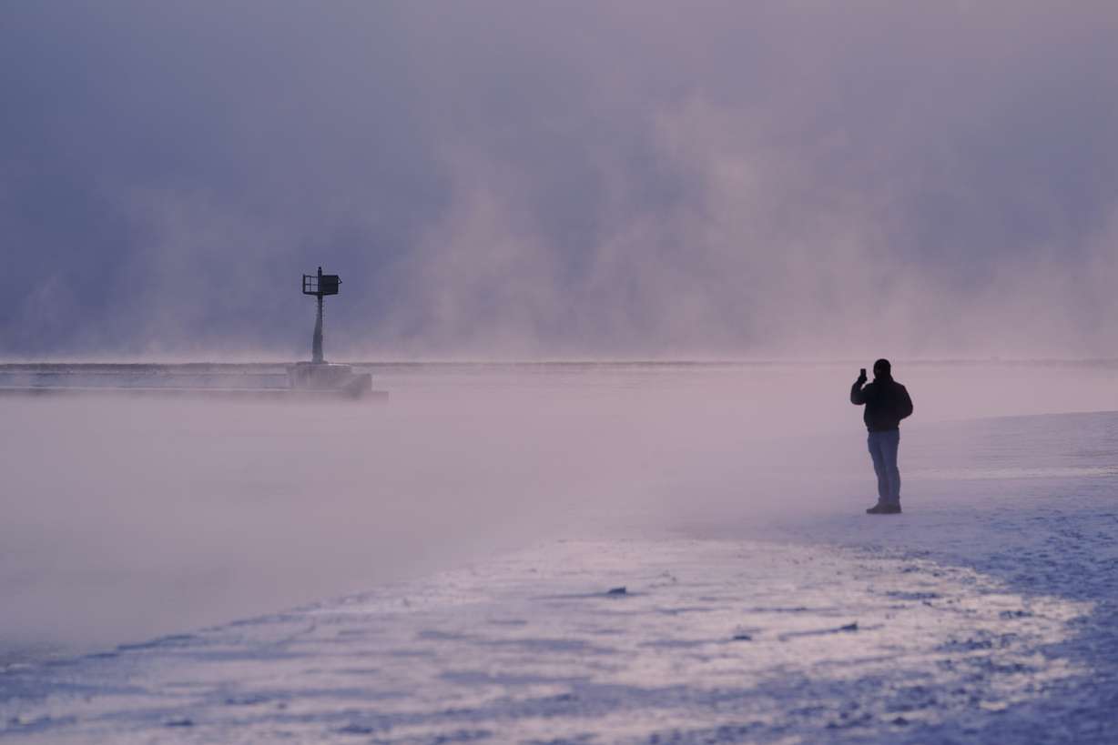 A person walks on an ice covered beach along the shore of Lake Michigan, Friday, in Chicago. While extreme cold is a concern coast to coast, the Northeast could see its heaviest snow in years.