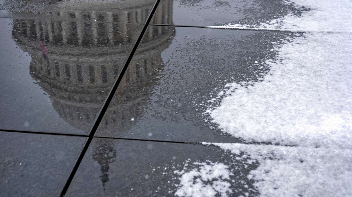 The dome of the Capitol reflected in a puddle of melted snow during the first snowfall of the winter on Dec. 5 in Washington. A major winter storm this weekend could cause travel delays for senators — and possibly lead to another government shutdown.
