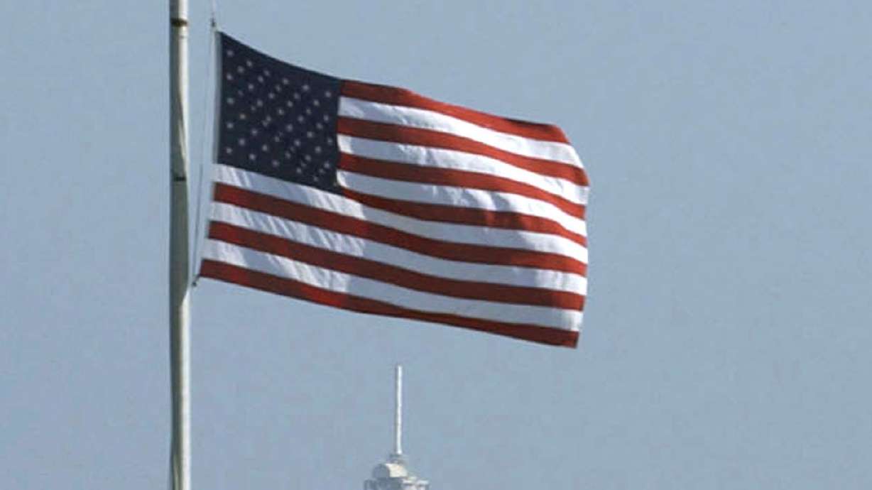 The American flag is lowered to half-staff at the press site with launchpad 39A in the background, at Kennedy Space Center on Feb. 1, 2003, following the Space Shuttle Columbia disaster.