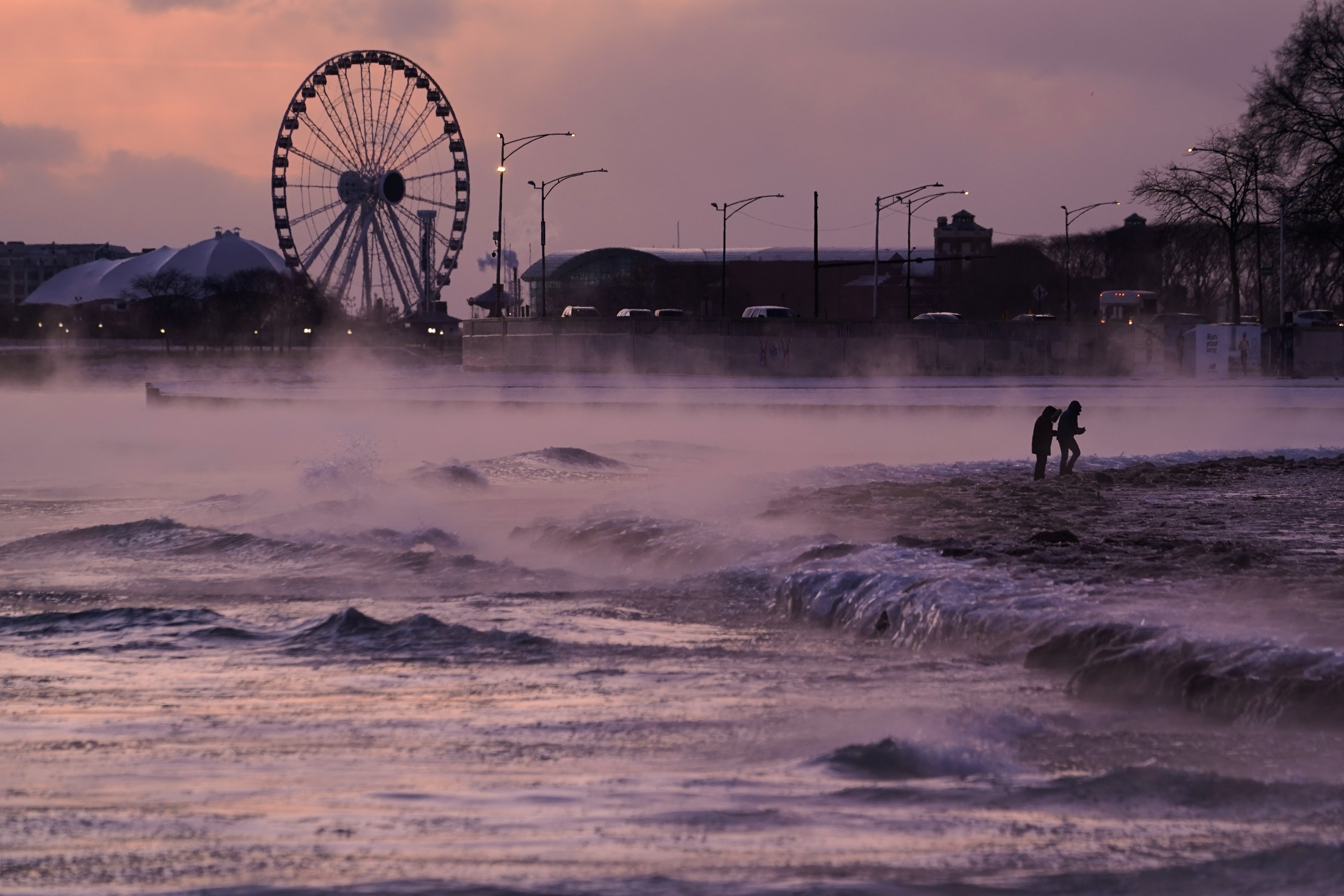 People walk on an ice covered beach along the shore of Lake Michigan, Friday in Chicago. 