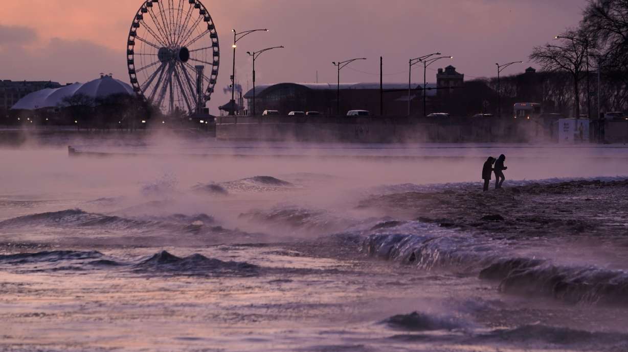 People walk on an ice covered beach along the shore of Lake Michigan, Friday in Chicago.