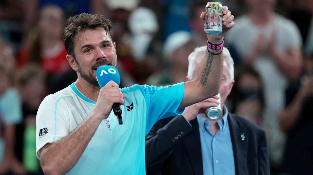 Stan Wawrinka of Switzerland holds up a beer following his third round loss to Taylor Fritz of the U.S. at the Australian Open tennis championship in Melbourne, Australia, Saturday, Jan. 24, 2026.
