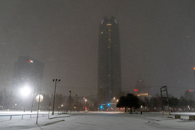 Snow falls over downtown as Winter Storm Fern arrives in Oklahoma City, Okla., Friday. Electric grid operators on Saturday stepped up precautions to avoid rotating blackouts as frigid weather hitting half of the country's population stressed their operations.