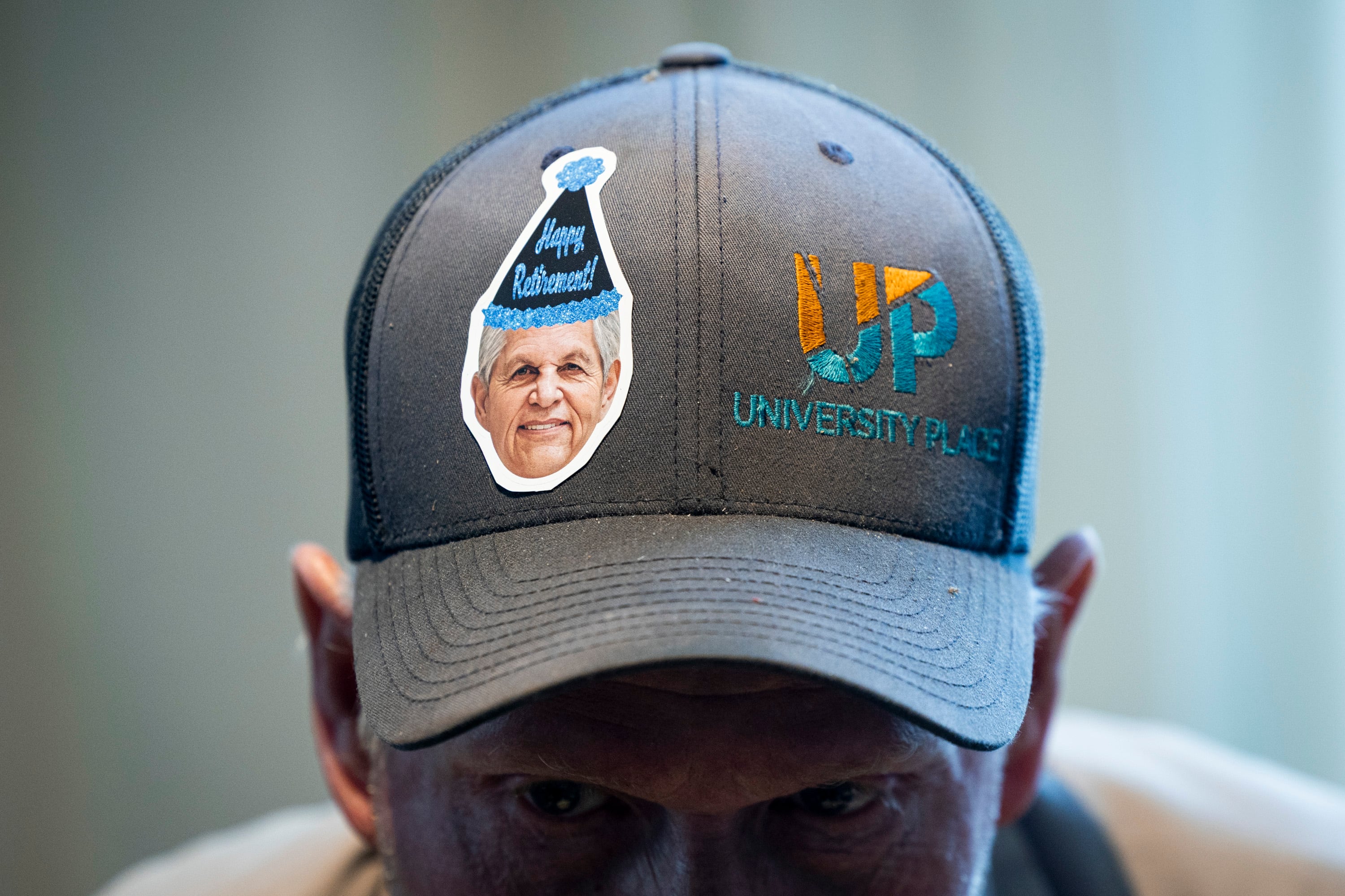 Randy Hainsworth, a member of the maintenance crew at University Place, eats his meal while sporting a sticker featuring the face of Rob Kallas, outgoing general manager for University Place, on his hat during a retirement party for Kallas, held at the Courtyard by Marriott Orem University Place hotel on Jan. 15.