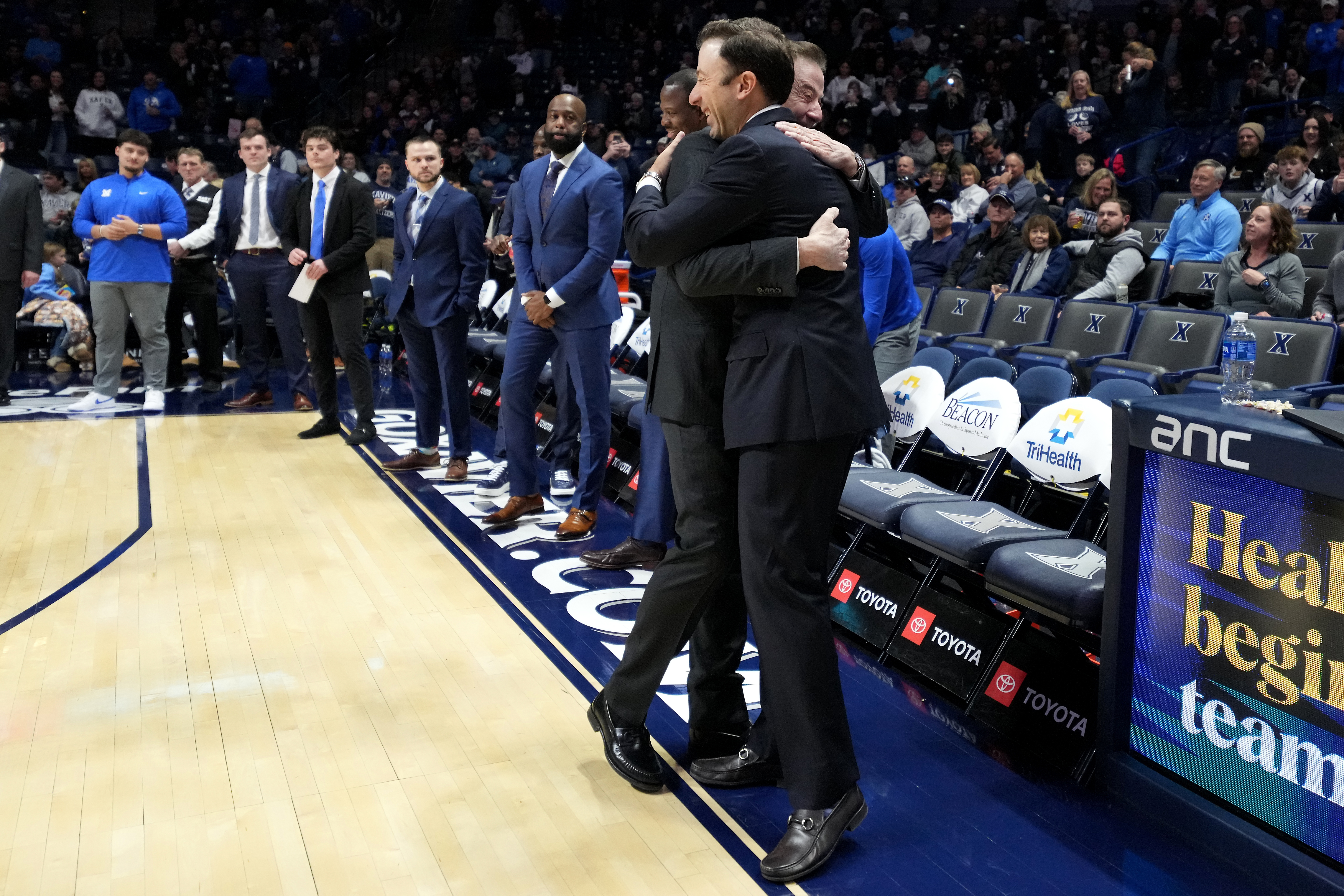 Xavier head coach Richard Pitino, right. wearing a full suit like his father, Rick Pitino, left, embraces him before a college basketball game St. John's, Saturday, Jan. 24, 2026, in Cincinnati. 