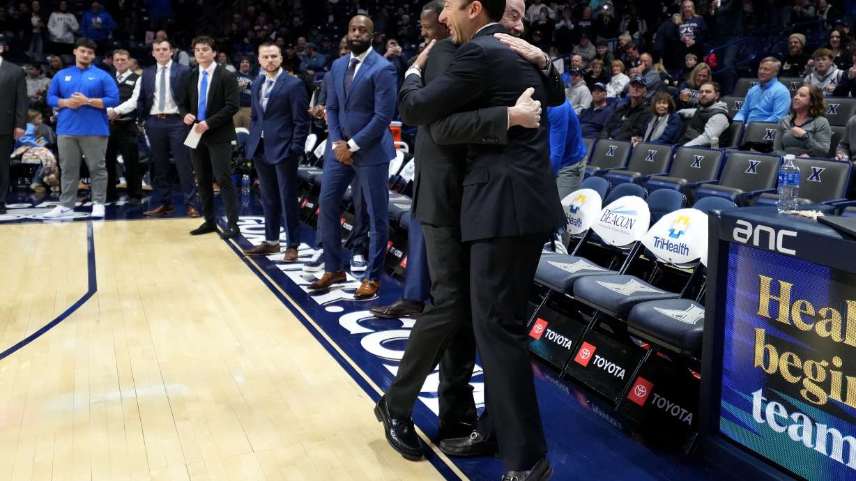 Xavier head coach Richard Pitino, right. wearing a full suit like his father, Rick Pitino, left, embraces him before a college basketball game St. John's, Saturday, Jan. 24, 2026, in Cincinnati.