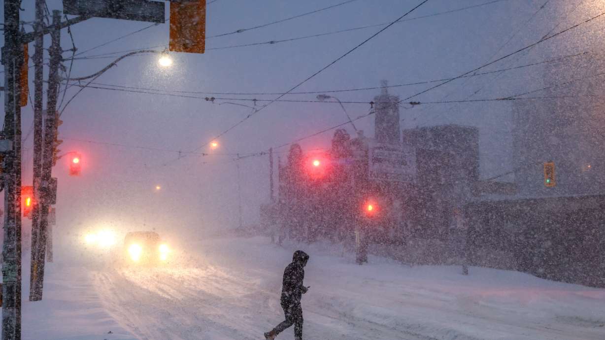 People walk through downtown Toronto as a winter storm moves through the region, Sunday. Many U.S. residents are facing another night of below-freezing temperatures and no electricity after a massive winter storm dumped more snow in Northeast and left parts of the South coated in ice.