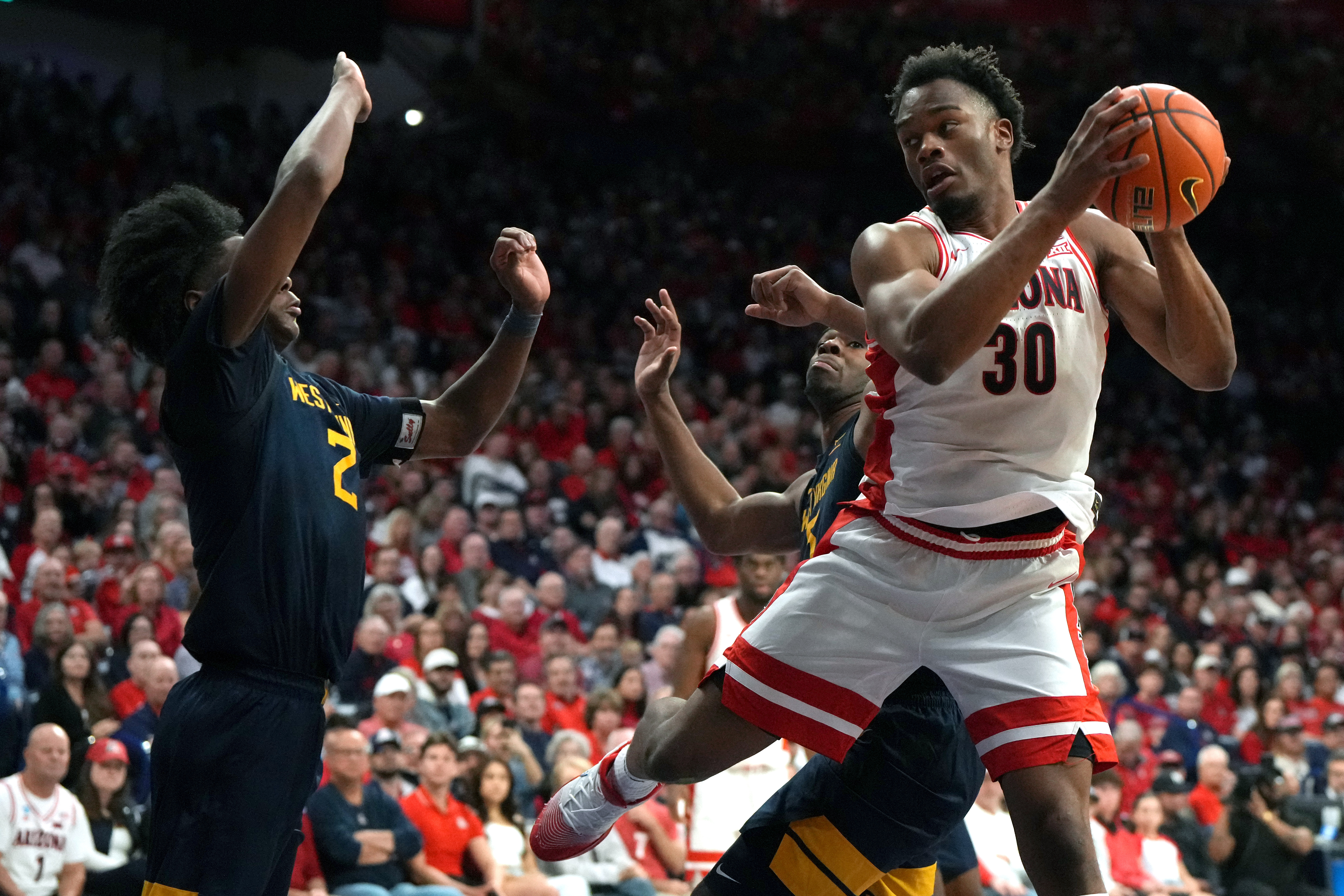 Arizona forward Tobe Awaka drives on West Virginia guard Amir Jenkins (2) and guard Honor Huff during the second half of an NCAA college basketball game, Saturday, Jan. 24, 2026, in Tucson, Ariz. 