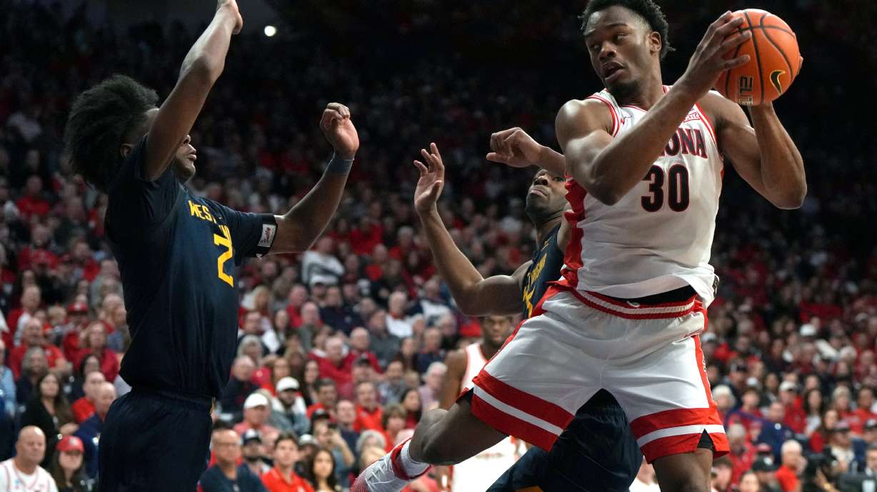Arizona forward Tobe Awaka drives on West Virginia guard Amir Jenkins (2) and guard Honor Huff during the second half of an NCAA college basketball game, Saturday, Jan. 24, 2026, in Tucson, Ariz.