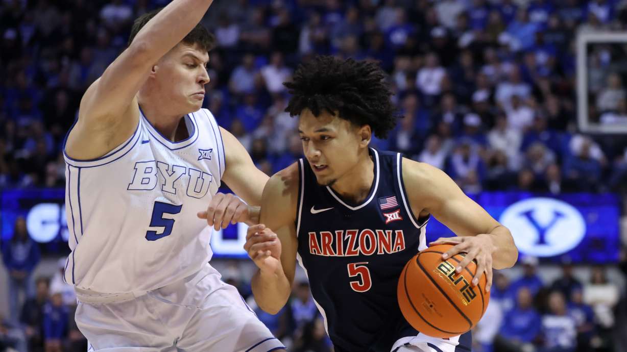 Arizona guard Brayden Burries, right, moves the ball as BYU forward Mihailo Boskovic (5) defends during the second half of an NCAA college basketball game, Monday, Jan. 26, 2026, in Provo, Utah.