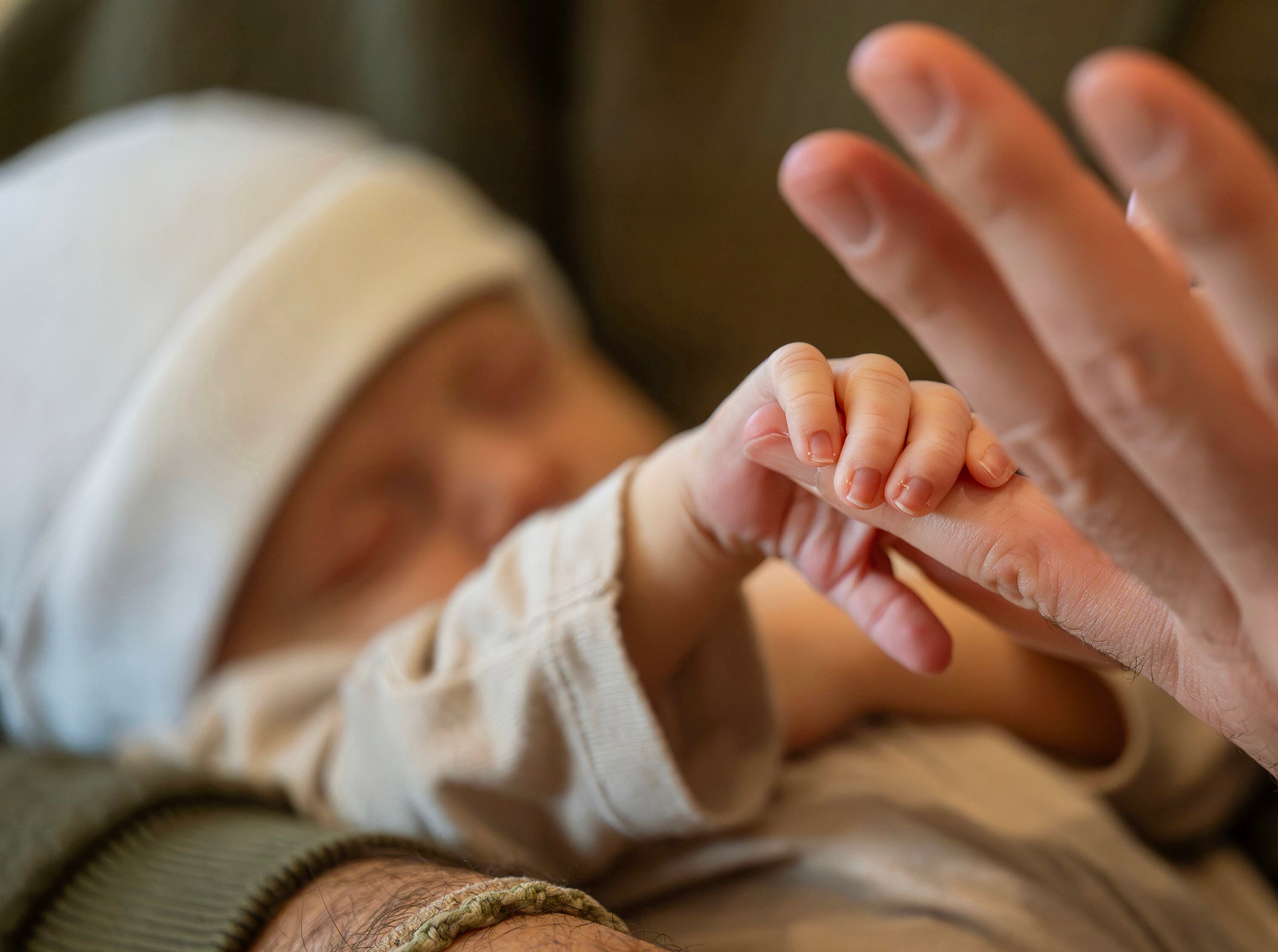 Newborn Vincent Golden Goodwin grips his dad’s finger while being held by his father, Jeff Goodwin, as Jeff and Bre Goodwin and big sister Murphy pose for photos at home in Bountiful on Saturday.