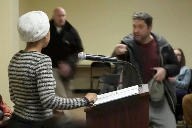 A man shouts at Rep. Ilhan Omar, D-Minn., after spraying her, during a town hall meeting days after a man identified as Alex Pretti was fatally shot by federal immigration agents trying to detain him, in Minneapolis, Minn., Tuesday.