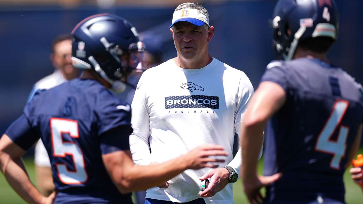FILE - Denver Broncos offensive coordinator Joe Lombardi, center, confers with Denver Broncos quarterbacks Ian Book (5) and Blake Stenstrom (4) as they take part in drills during the NFL football team's rookie minicamp, May 10, 2025, in Centennial, Colo.