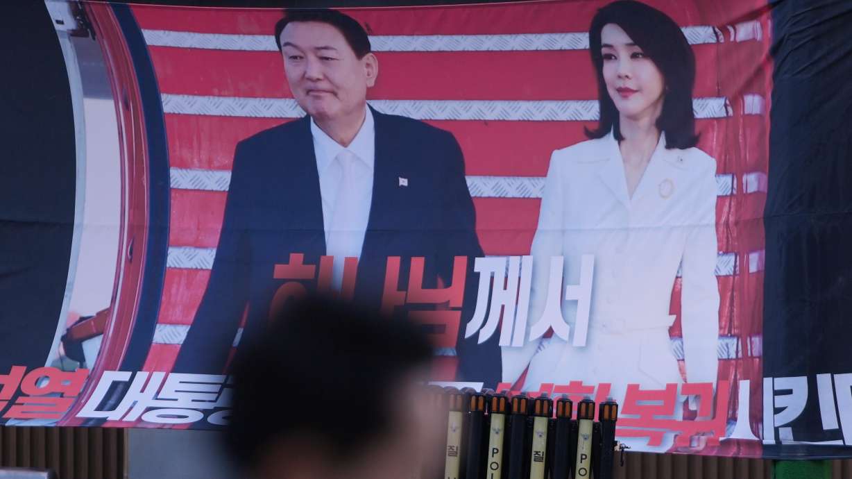 A man walks past near a banner showing the picture of former South Korean President Yoon Suk Yeol and his wife Kim Keon Hee, outside of Seoul Central District Court, in Seoul, South Korea, Jan. 13. The former first lady was sentenced to 20 months in prison for corruption.