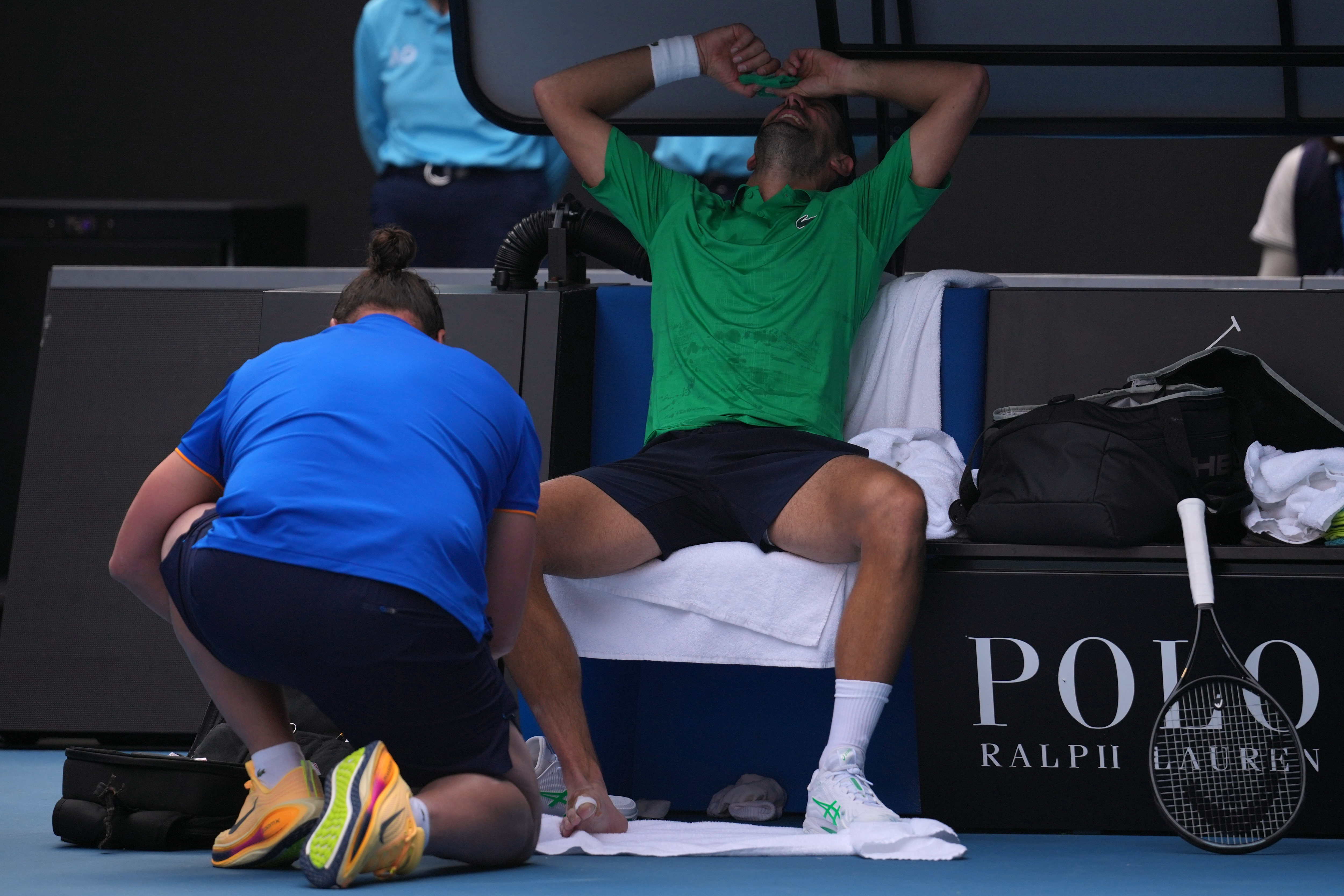 Novak Djokovic of Serbia reacts as he receives treatment to a foot injury during his quarterfinal match against Lorenzo Musetti of Italy at the Australian Open tennis championship in Melbourne, Australia, Wednesday, Jan. 28, 2026. 