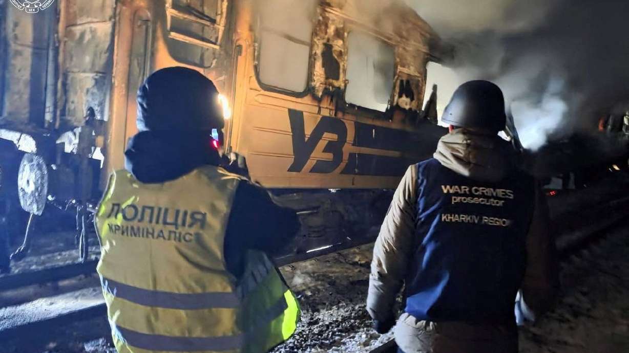 A war crime prosecutor and a police officer work next to a passenger train hit by a Russian drone strike, amid Russia's attack on Ukraine, in Kharkiv, on Tuesday.