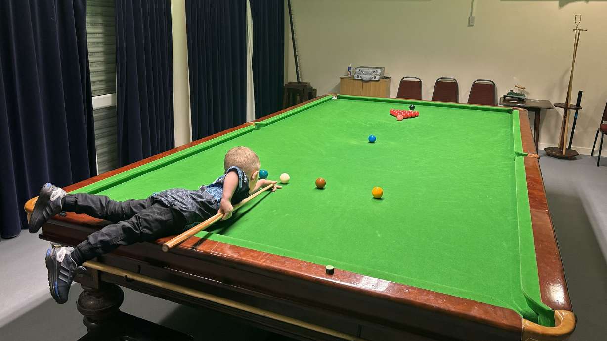 Jude has to use a stool in order to reach the table and play.