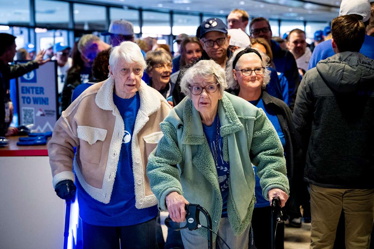 Penny Spresser, 86, center right, walks with her sister, Dixie Grimmett, 89, as they make their way toward their seats before an NCAA men’s basketball game between BYU and Utah held at the Marriott Center in Provo on Jan. 24.