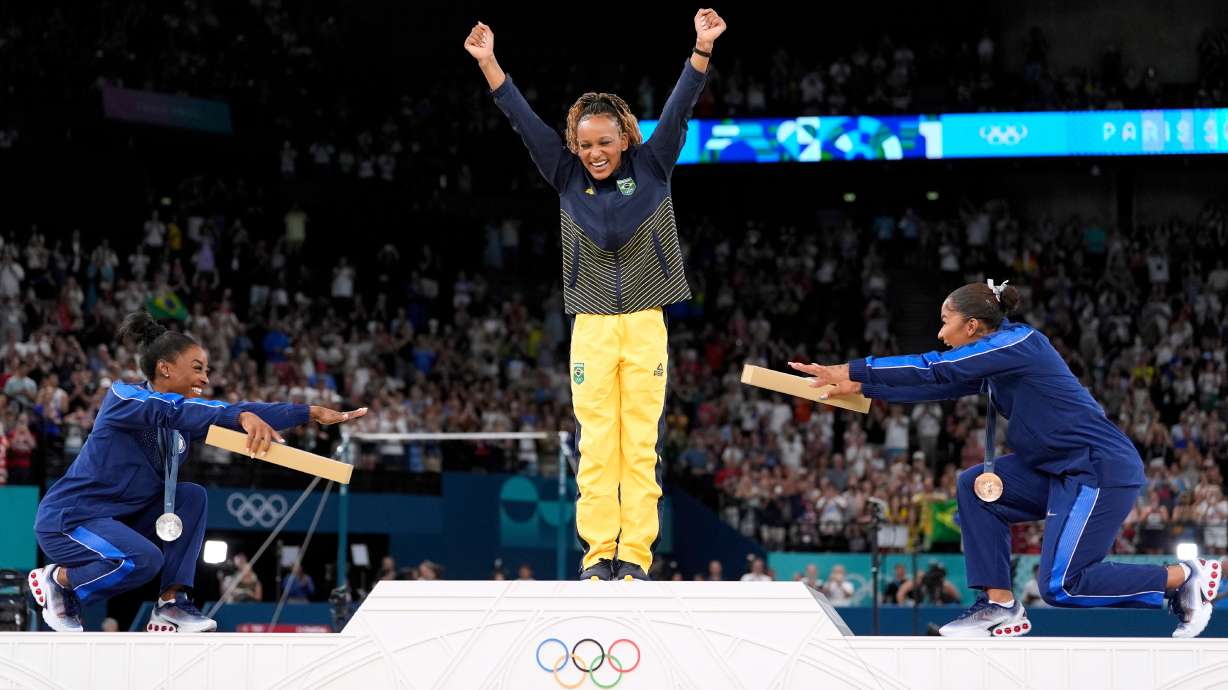 FILE - Silver medalist Simone Biles, of the United States, left, and bronze medalist Jordan Chiles, of the United States, right, bow to gold medalist Rebeca Andrade, of Brazil, during the medal ceremony for the women's artistic gymnastics individual floor finals at Bercy Arena at the 2024 Summer Olympics, Aug. 5, 2024, in Paris, France.