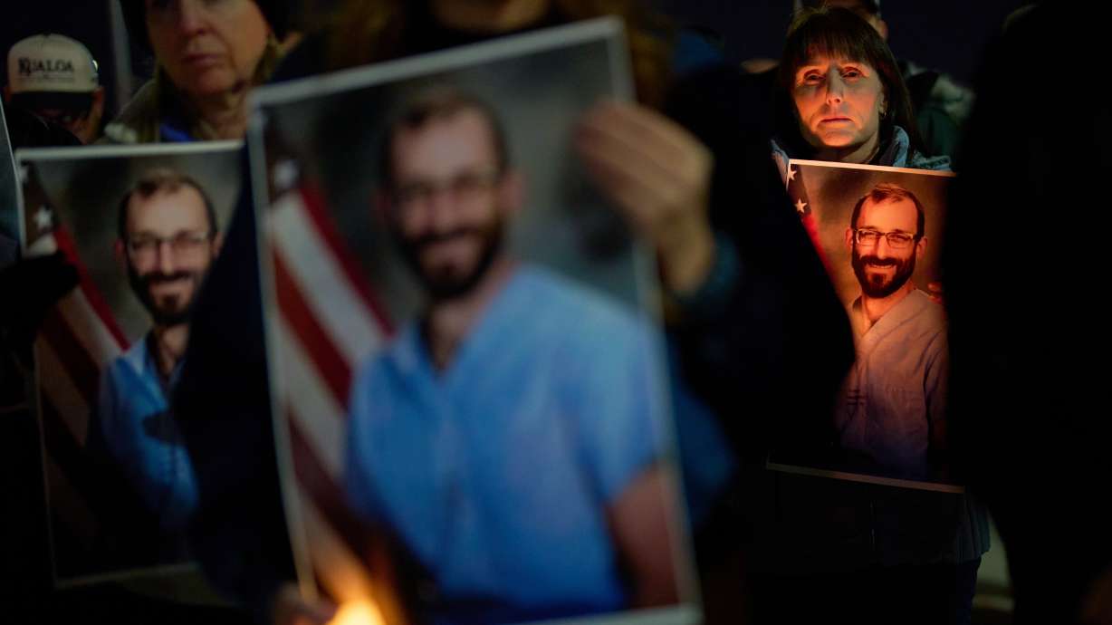 People hold up photos during a vigil for Alex Pretti, who was killed by federal immigration enforcement in Minneapolis, Wednesday, in Henderson, Nev. The Justice Department announced it opened a federal civil rights investigation into his death.