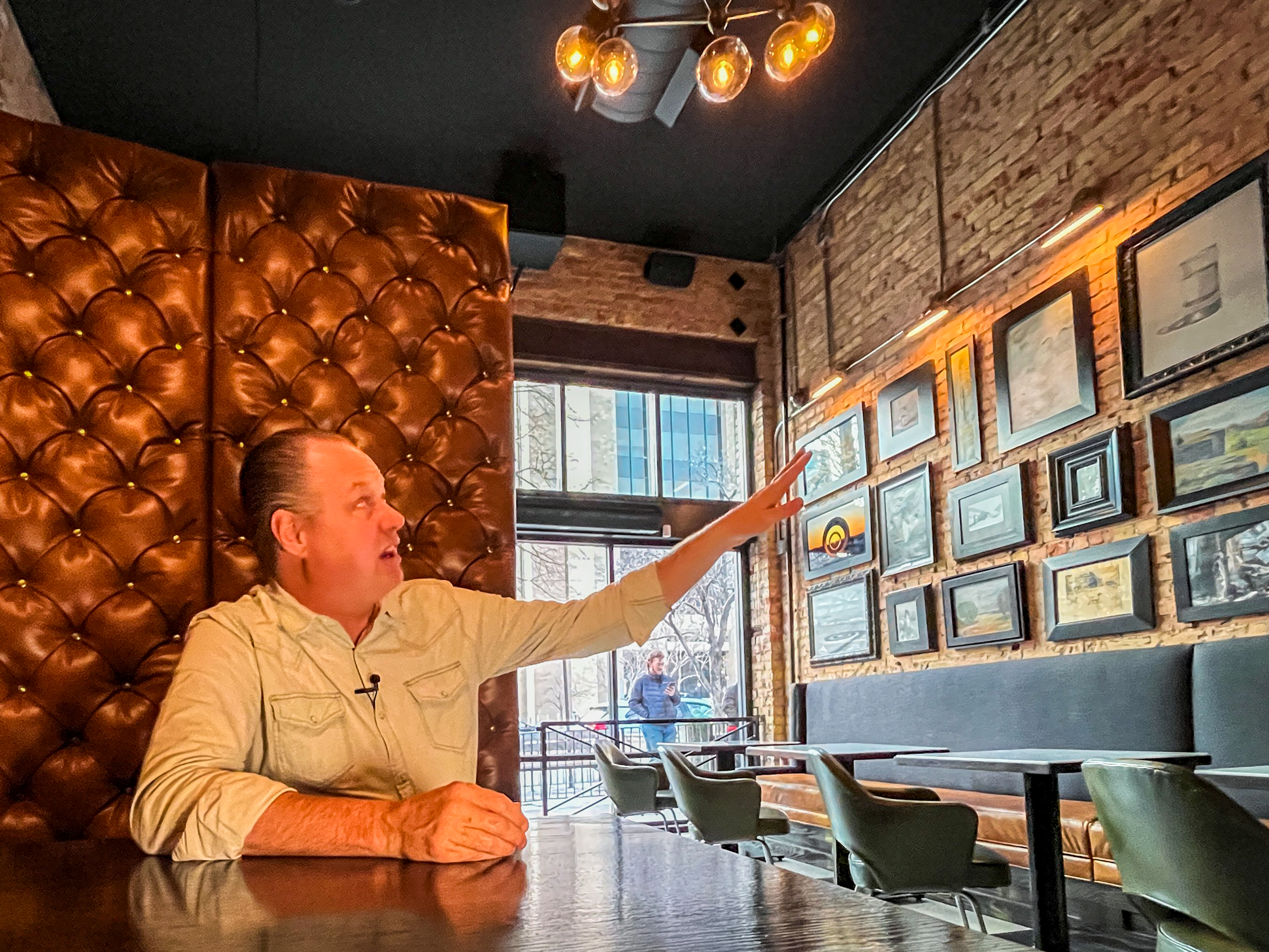 Jason LeCates, co-owner of White Horse Spirits & Kitchen, points to elements of the building's new interior before the business reopened on Thursday. Restaurant owners chose to keep the business's interior mostly the same after it was heavily damaged by last year's fire.